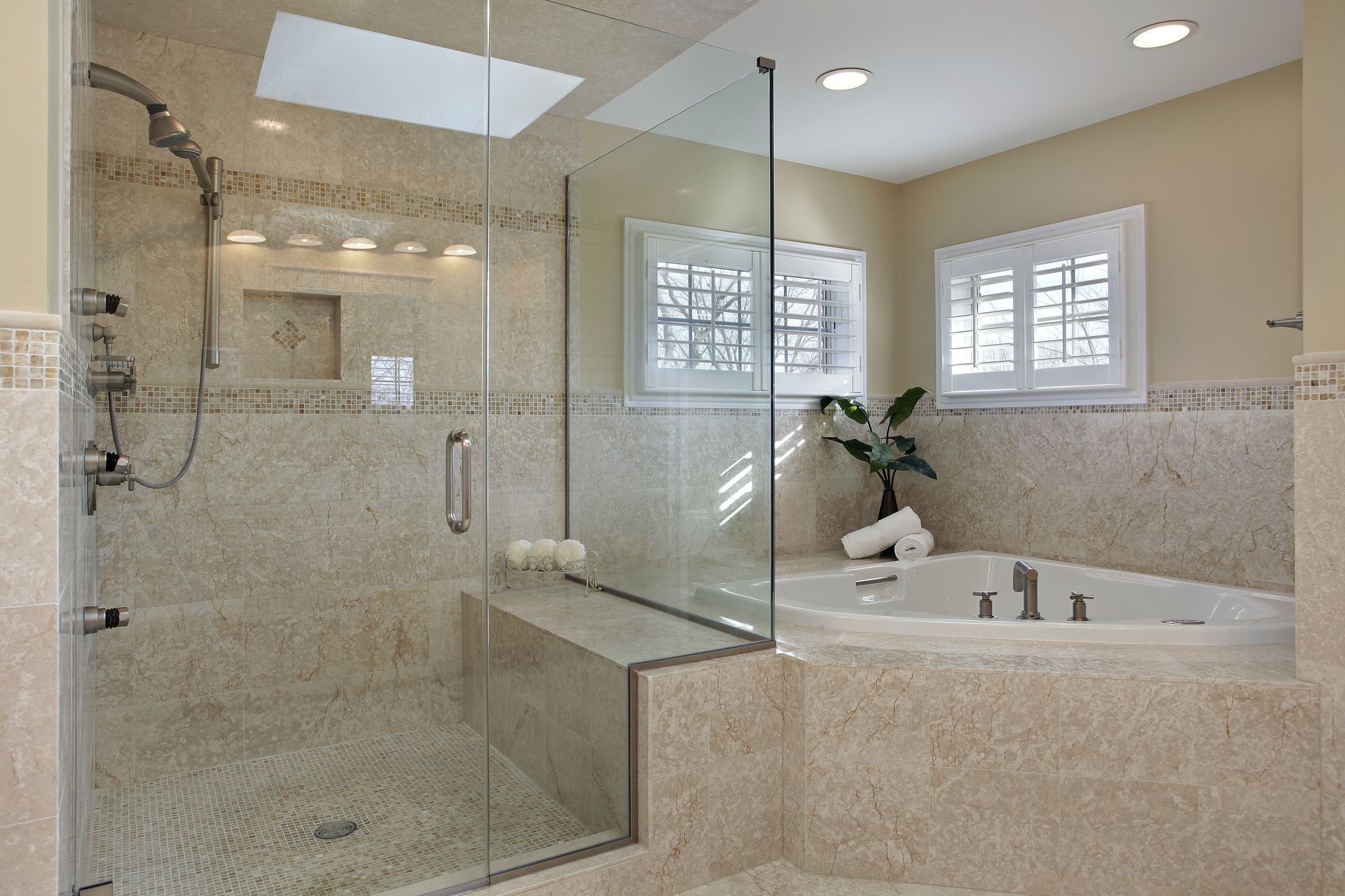 Luxurious bathroom with a glass shower, tub, and pebble tile walls.