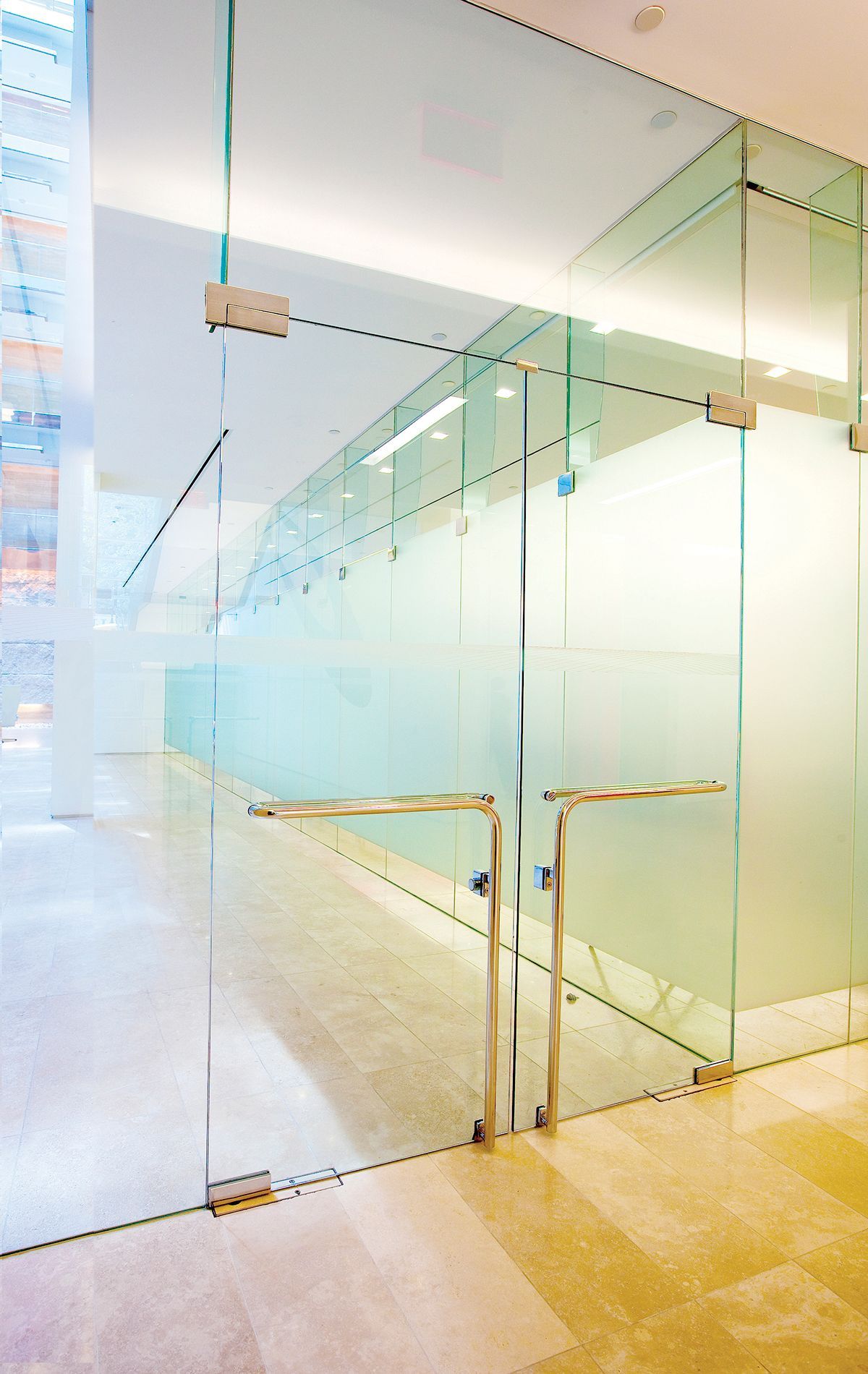 Glass-walled hallway with frosted glass and modern stainless steel door handles.