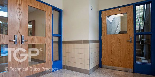 Hallway with wooden doors with glass windows; blue frames; cream wall and floor.