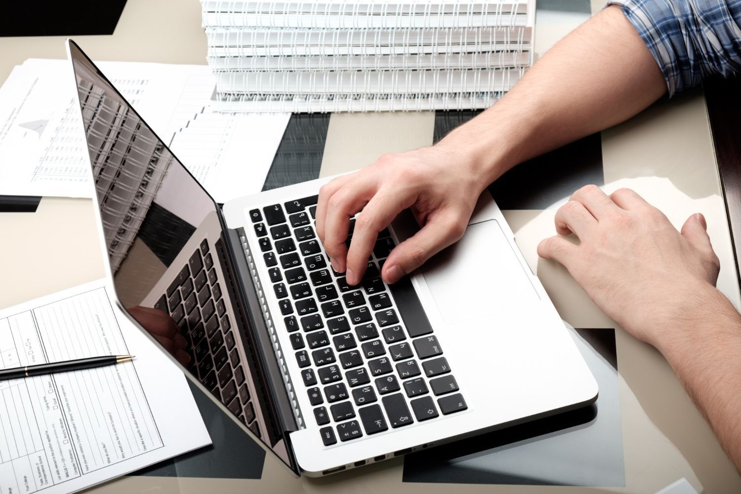 A person is typing on a laptop while sitting at a desk