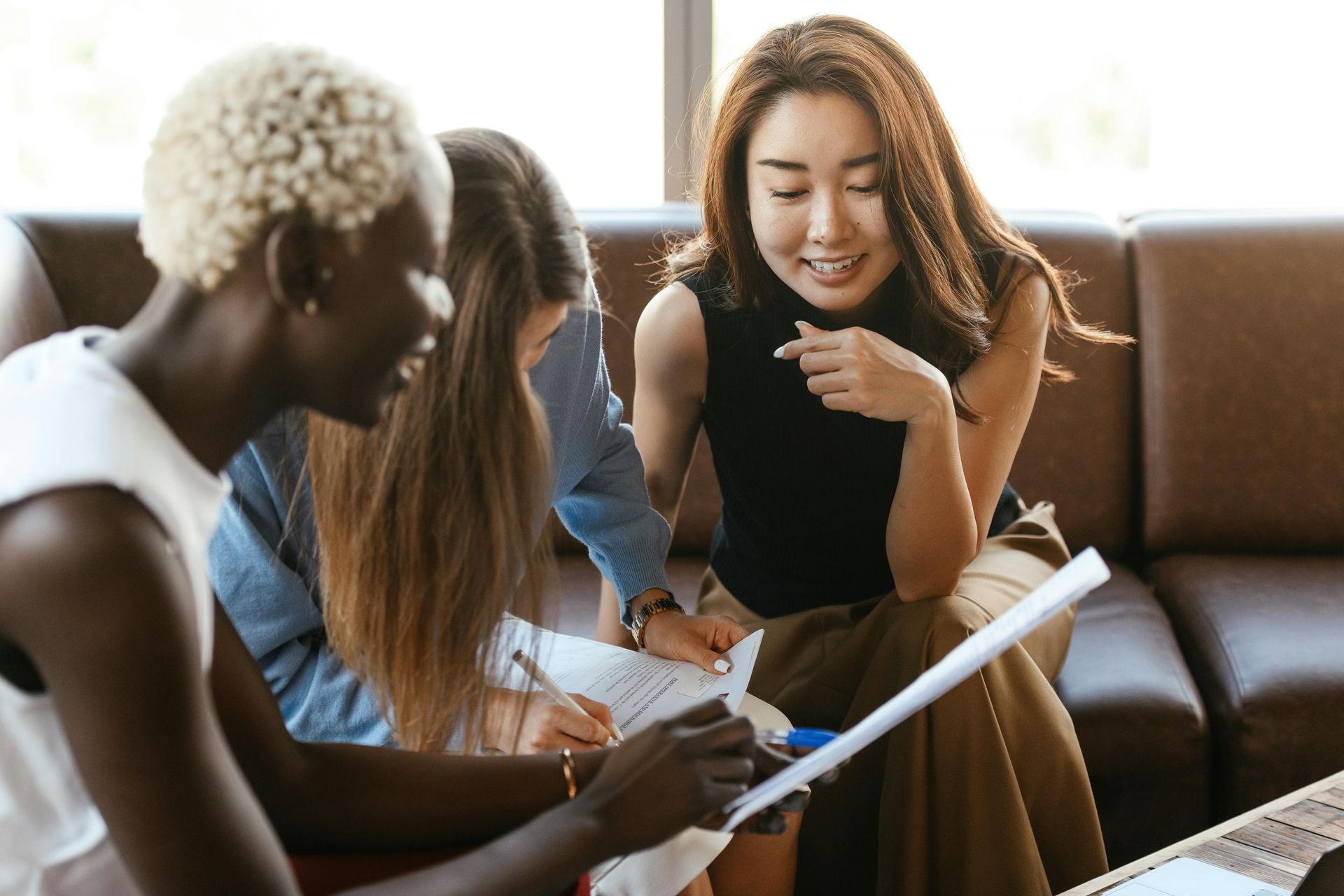 A group of people are sitting on a couch looking at a piece of paper.