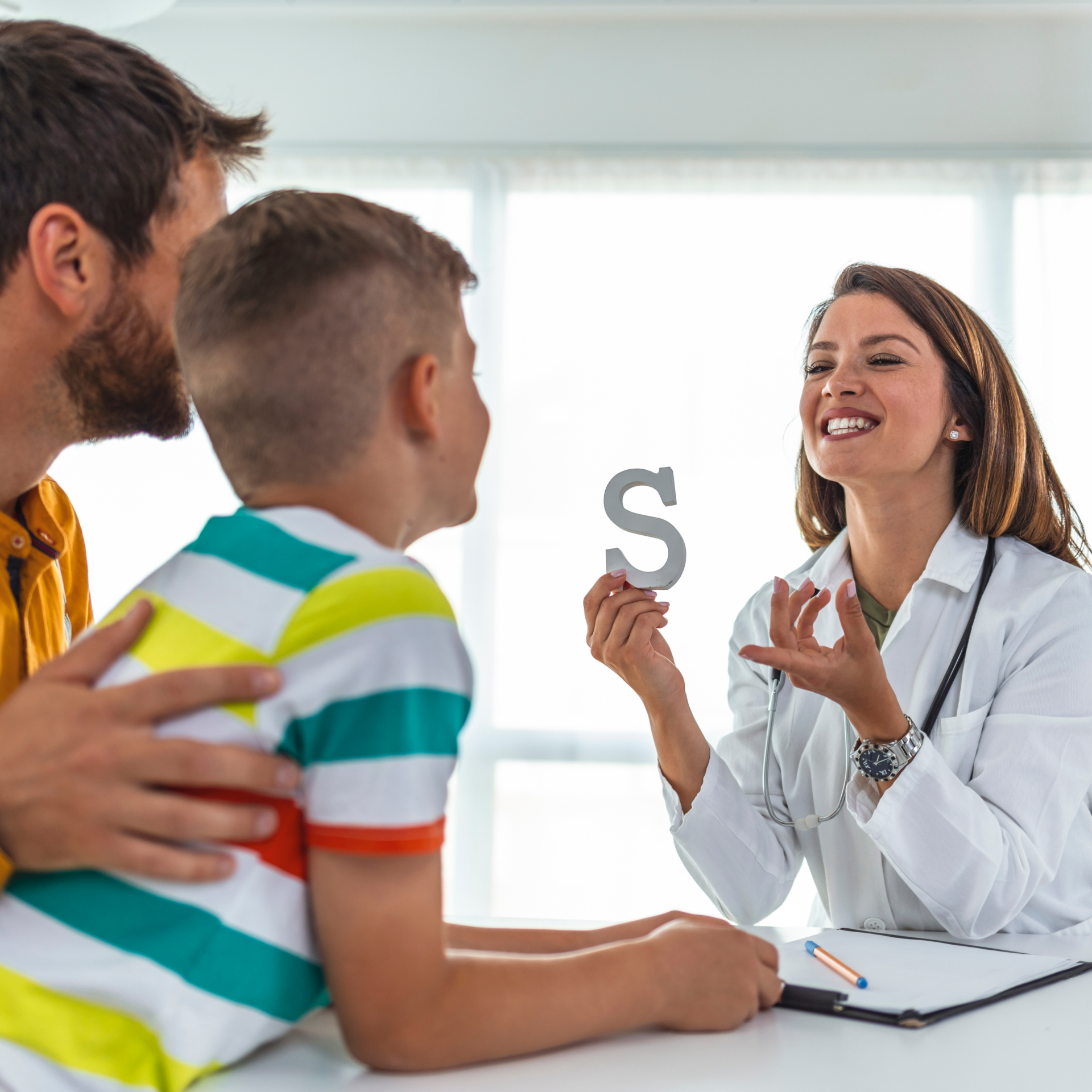 a doctor is talking to a child who is holding a letter s