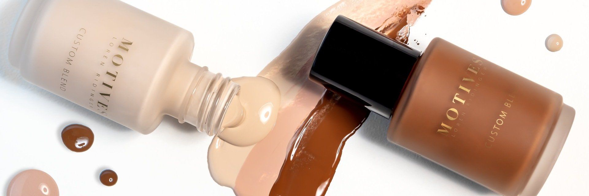 two bottles of foundation are sitting next to each other on a white surface .