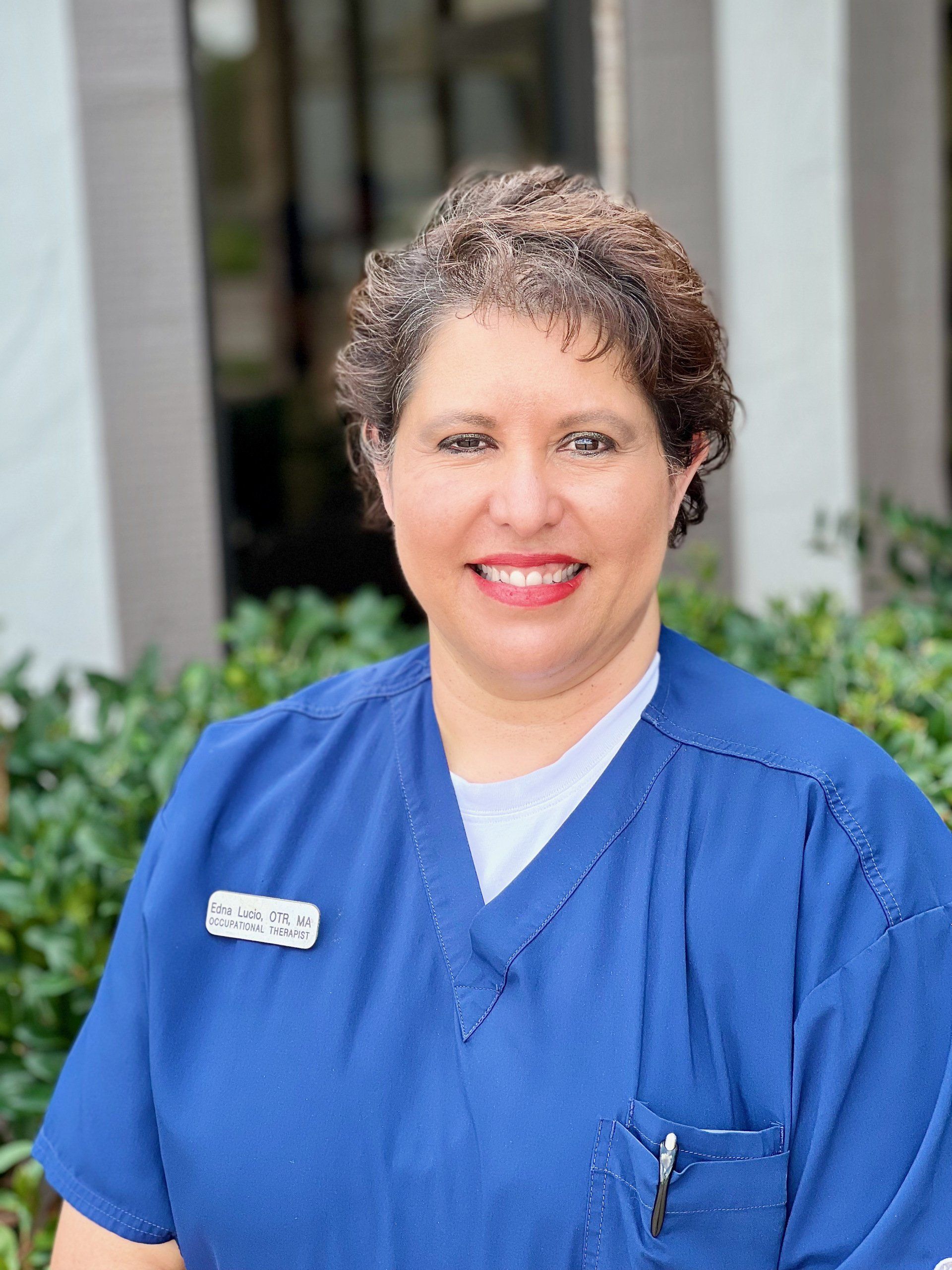 a woman in a blue scrub top is smiling for the camera .