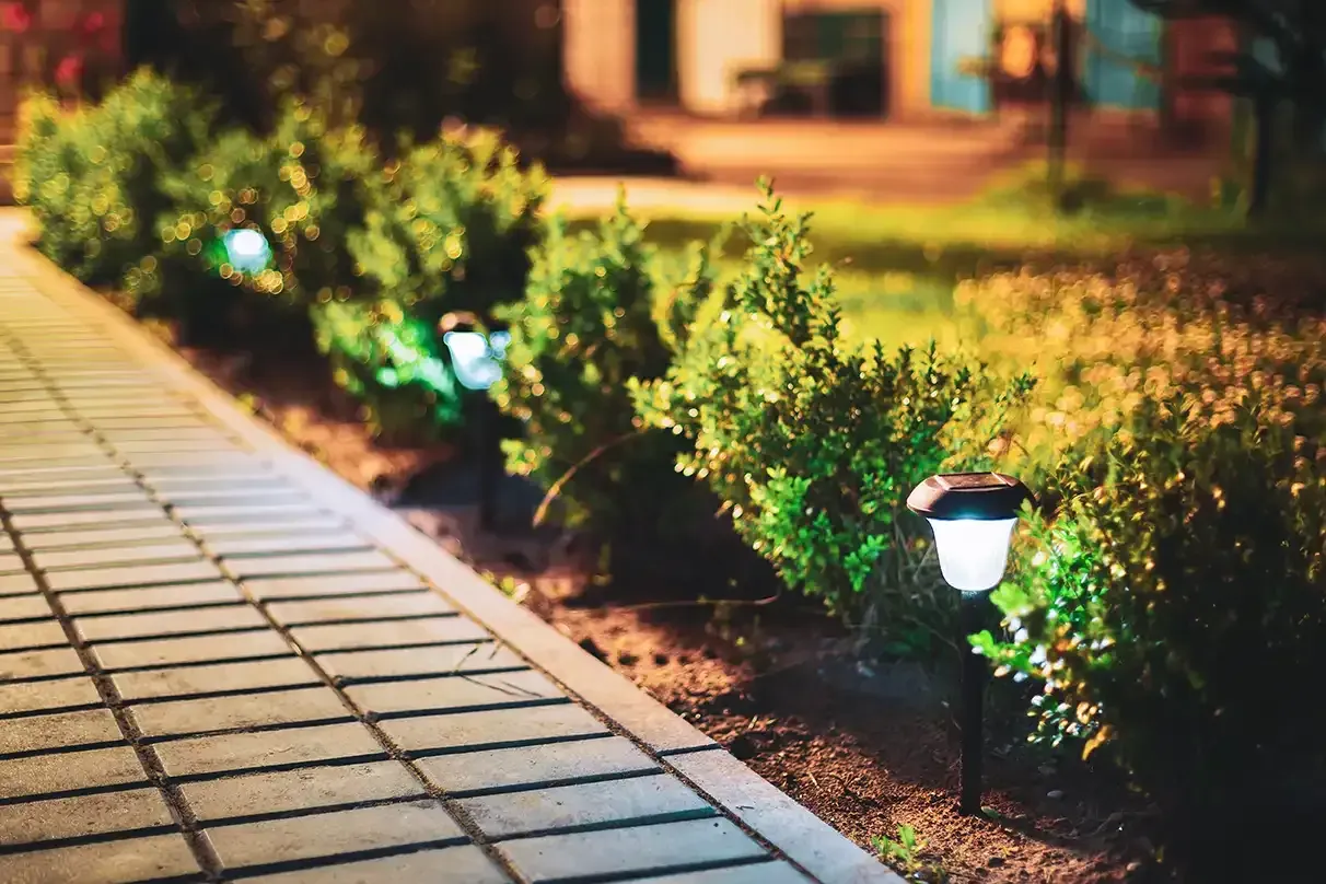A row of solar powered lights on a sidewalk at night.