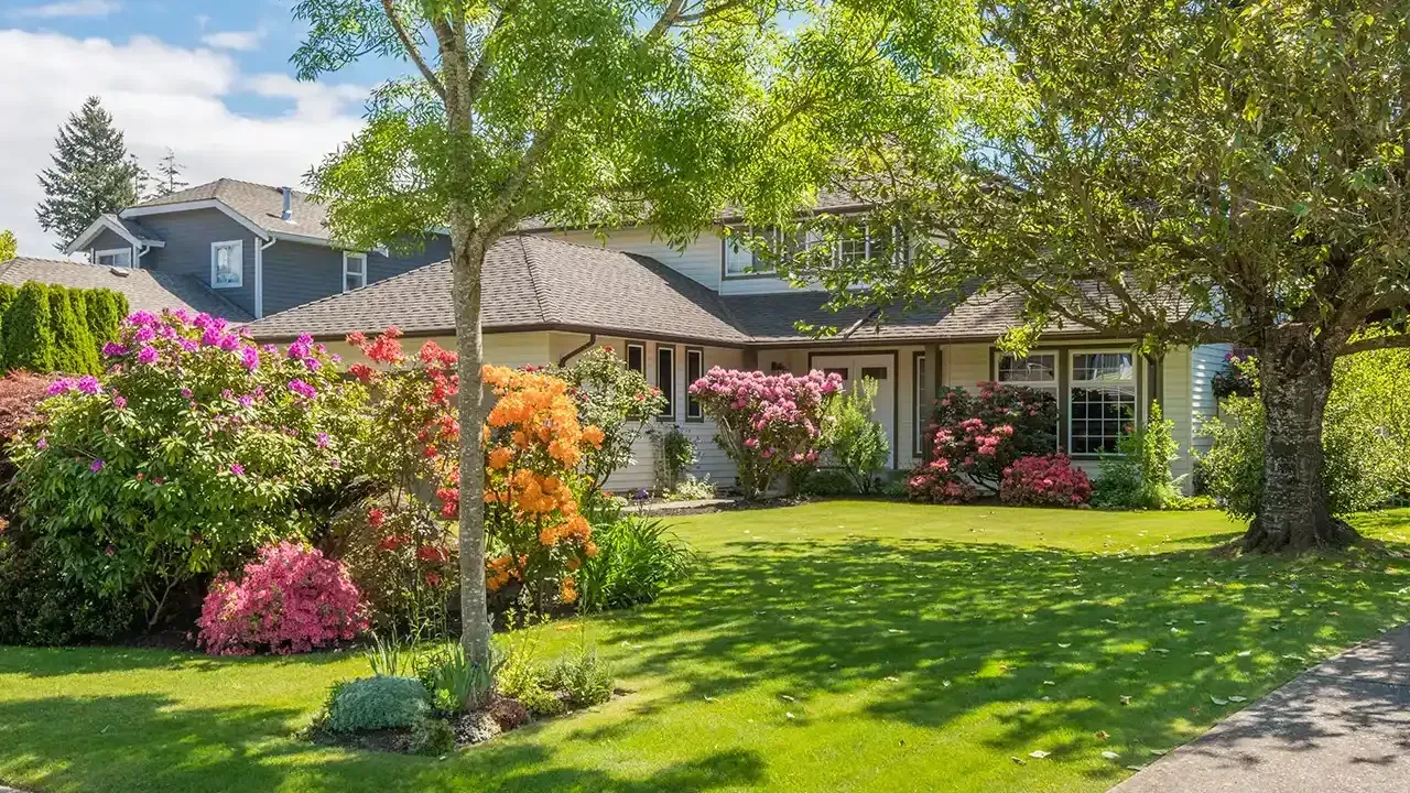 A house with a large lawn and flowers in front of it.