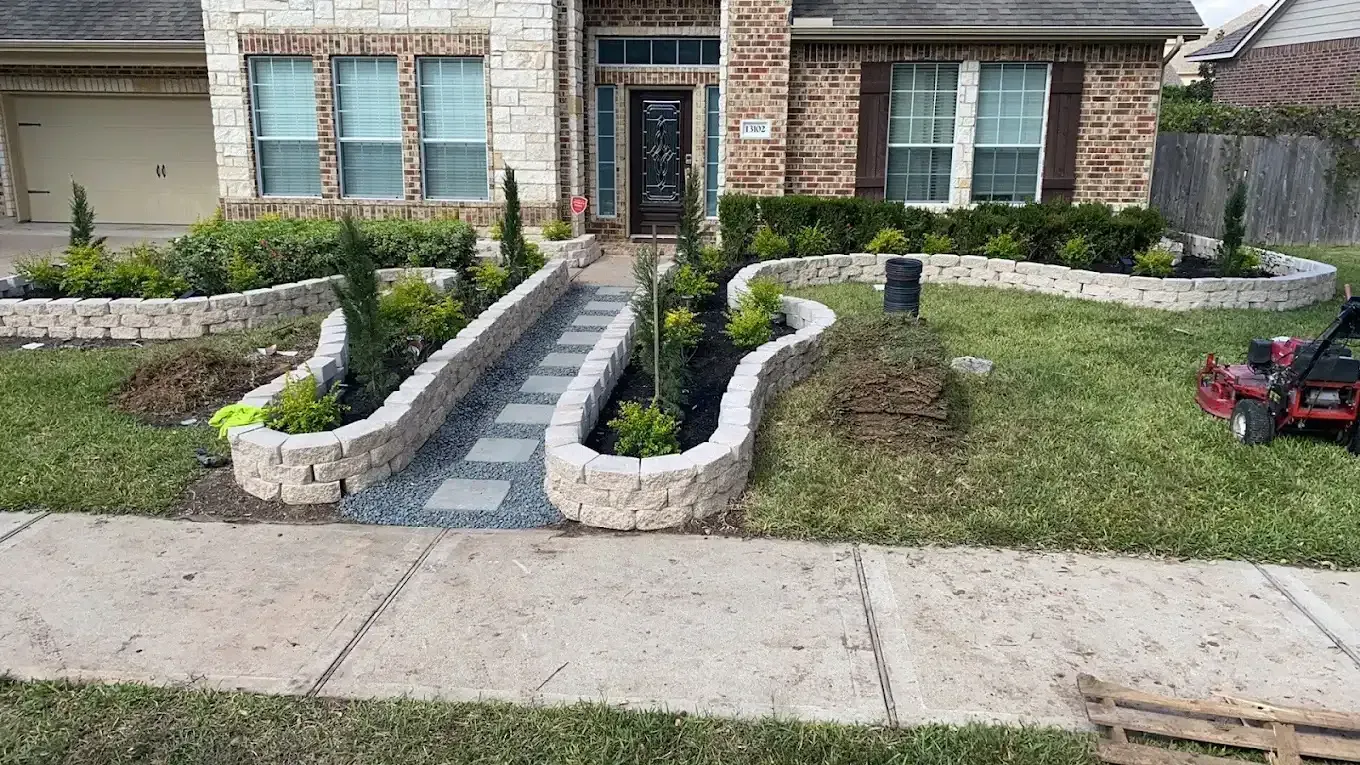 A lawn mower is parked in front of a brick house.
