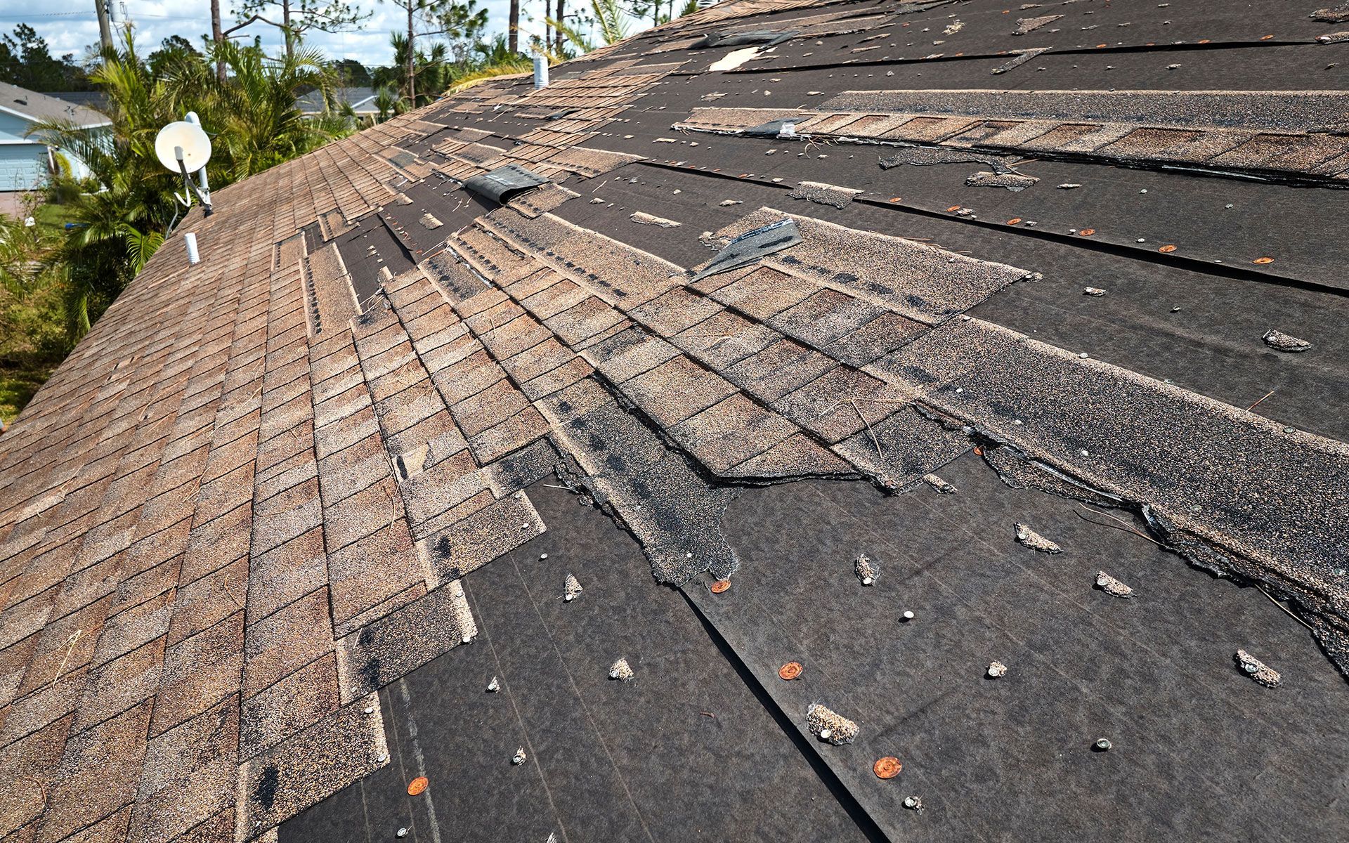 Damaged asphalt shingle roof with missing and deteriorated shingles.