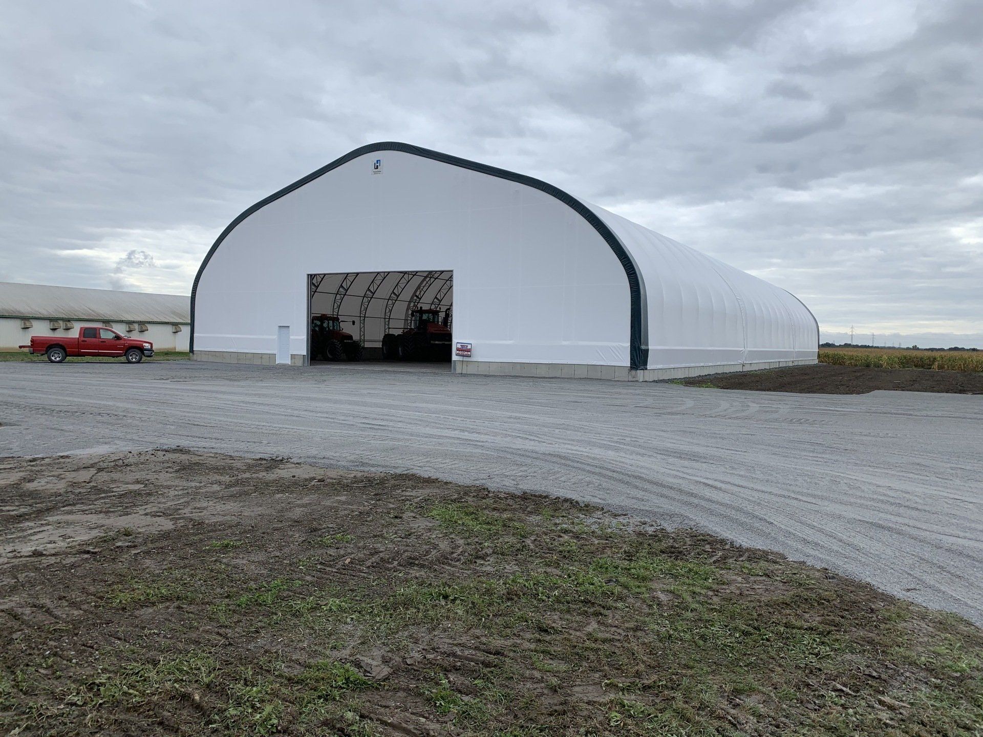Un camion rouge est garé devant un grand bâtiment blanc.