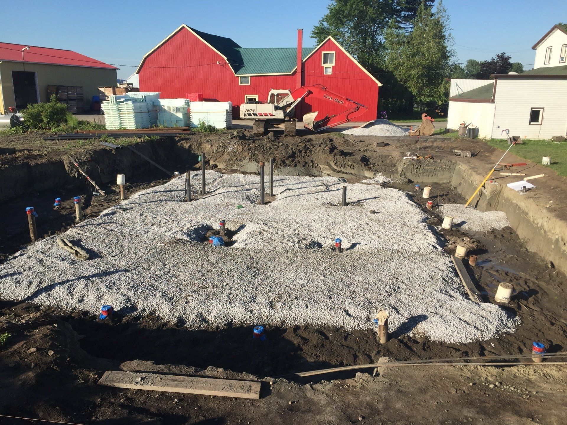 Un chantier de construction avec une grange rouge en arrière-plan.