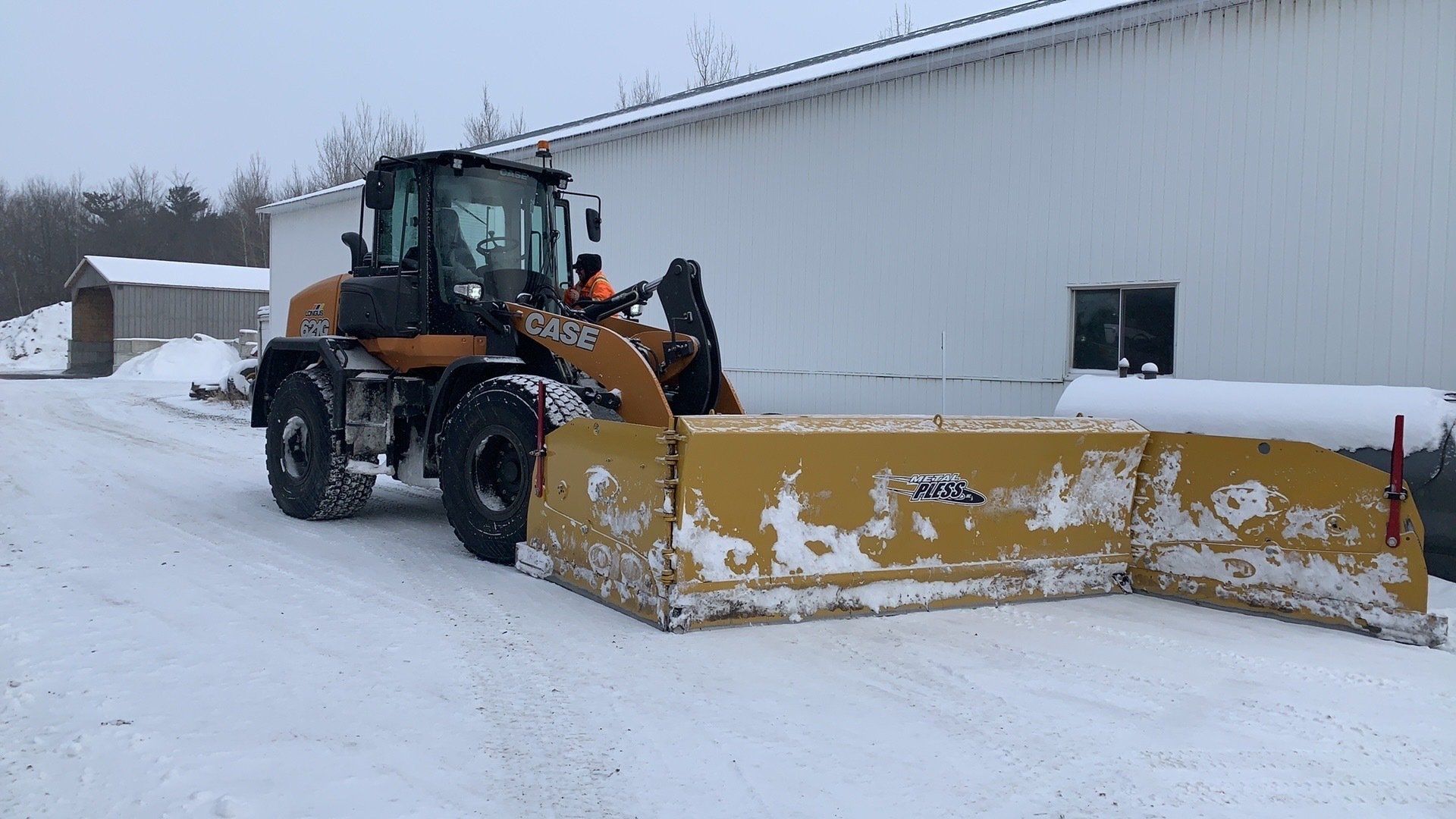 Un chasse-neige est garé dans la neige devant un bâtiment.