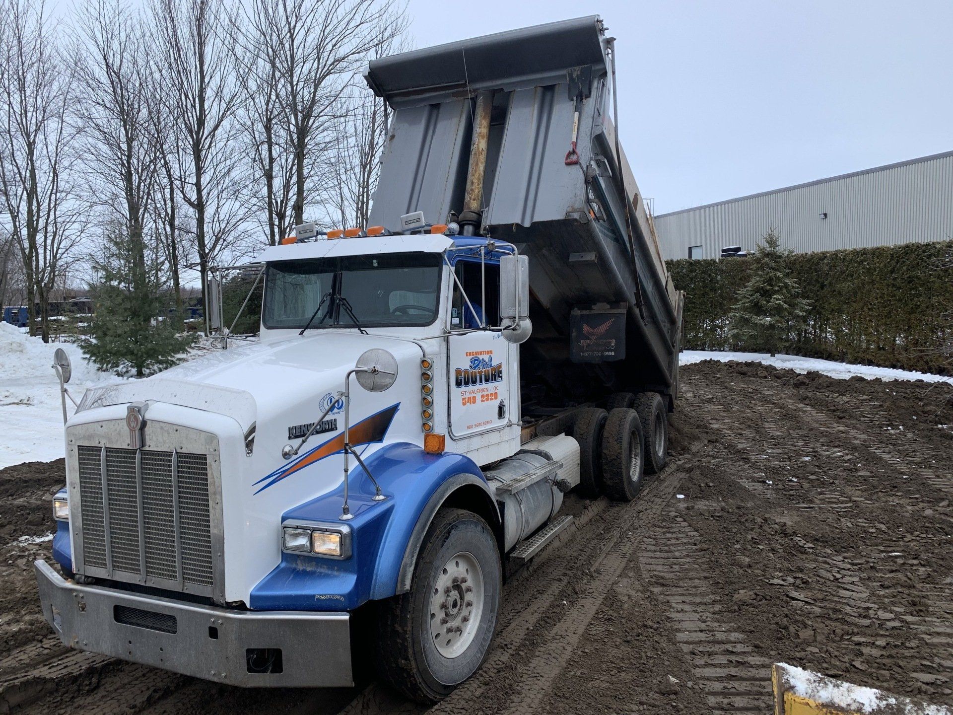 Un camion-benne roule sur un chemin de terre.