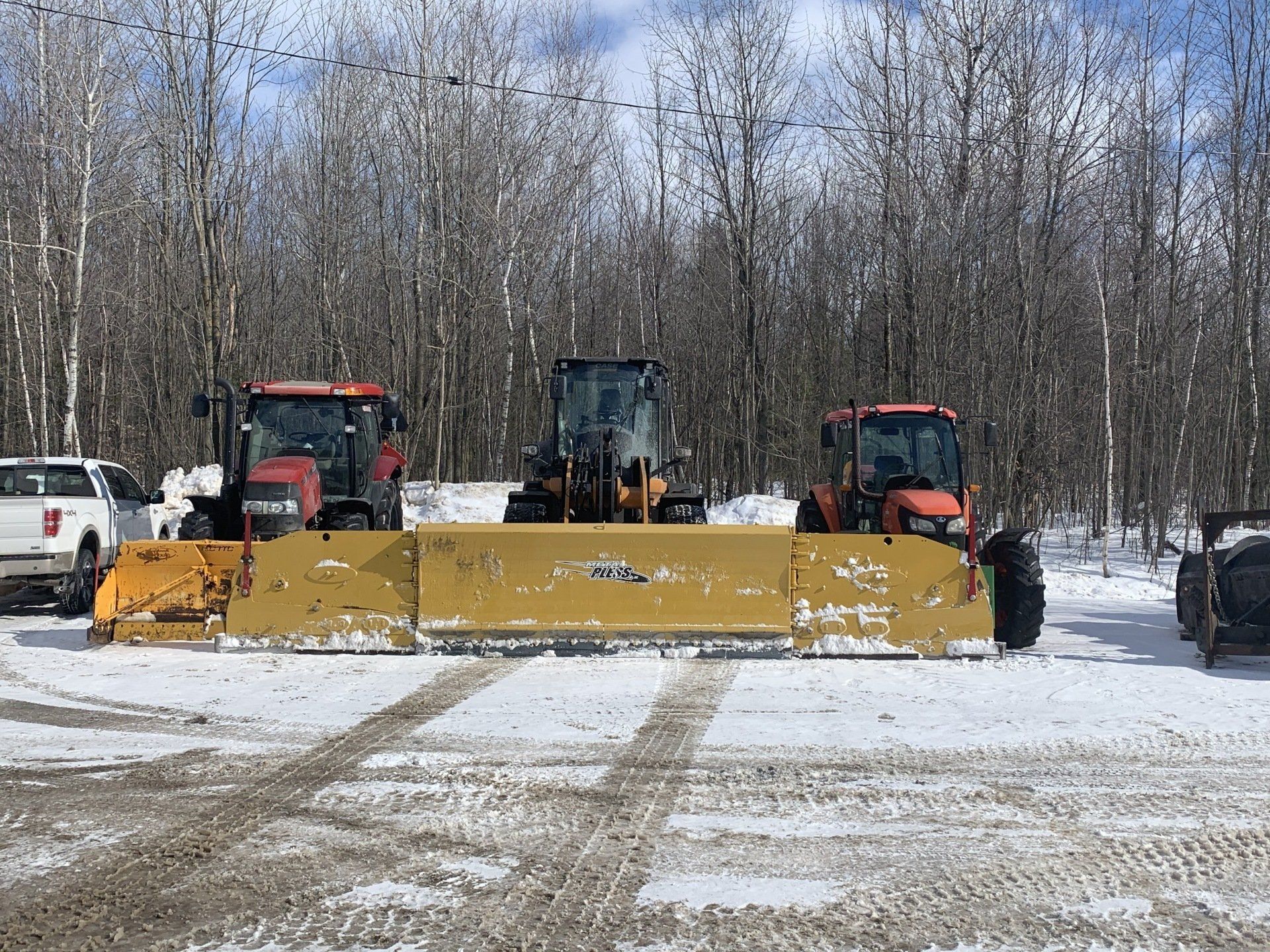 Deux tracteurs déneigent un parking.