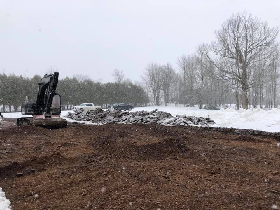 Une excavatrice déplace de la terre dans un champ enneigé.