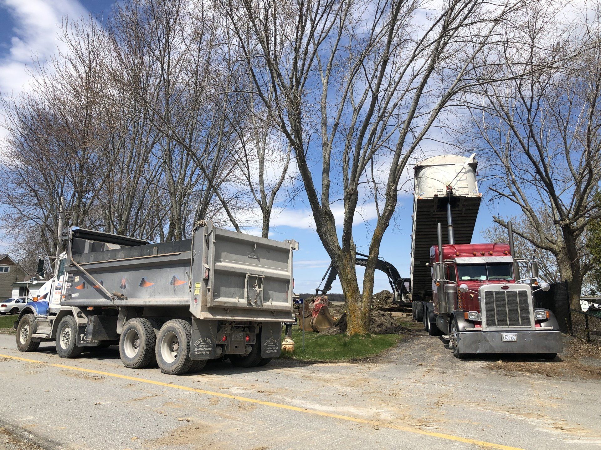 Deux camions bennes sont garés l’un à côté de l’autre sur le bord de la route.