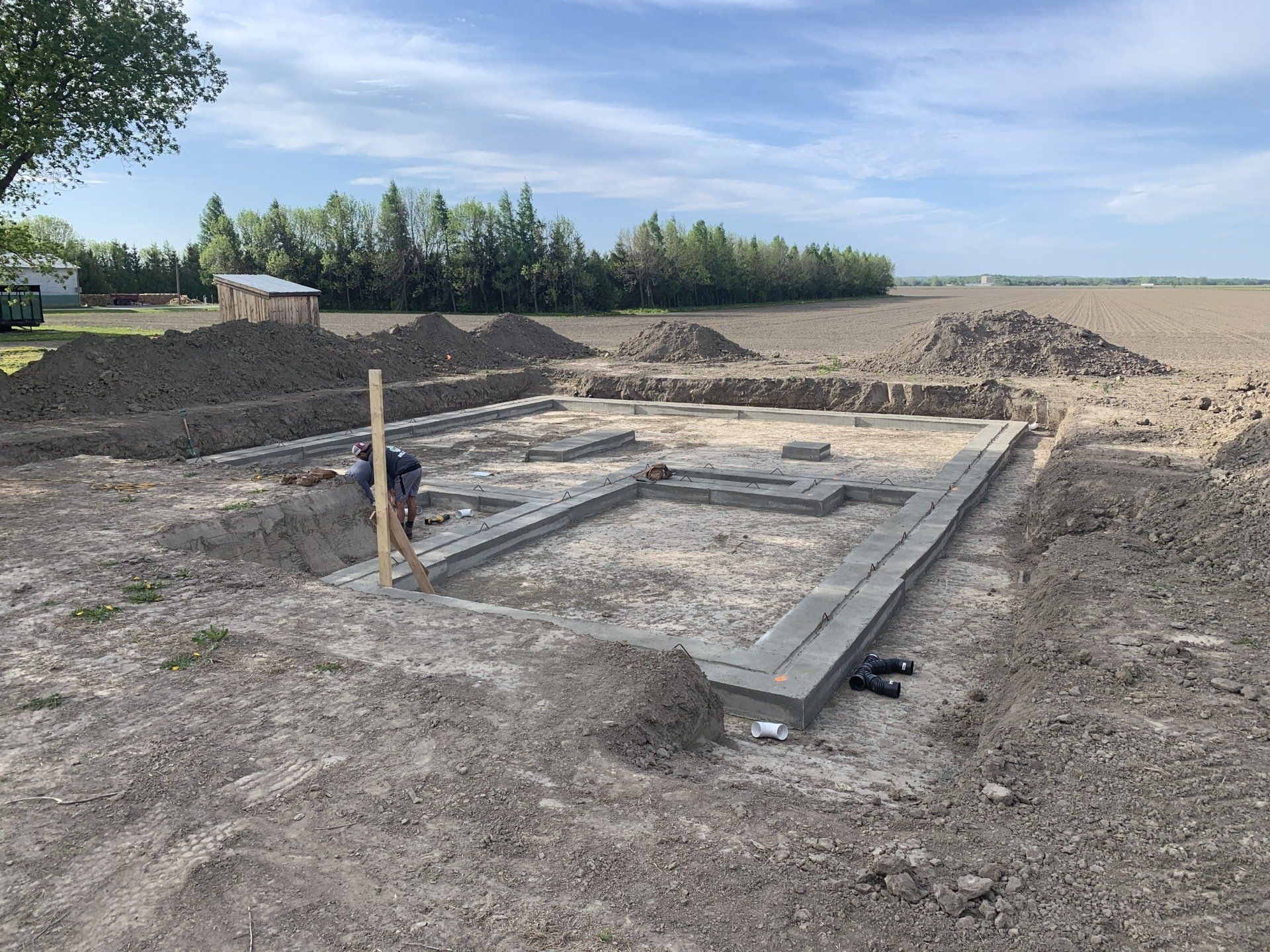 Une fondation en béton est en cours de construction dans un champ de terre.