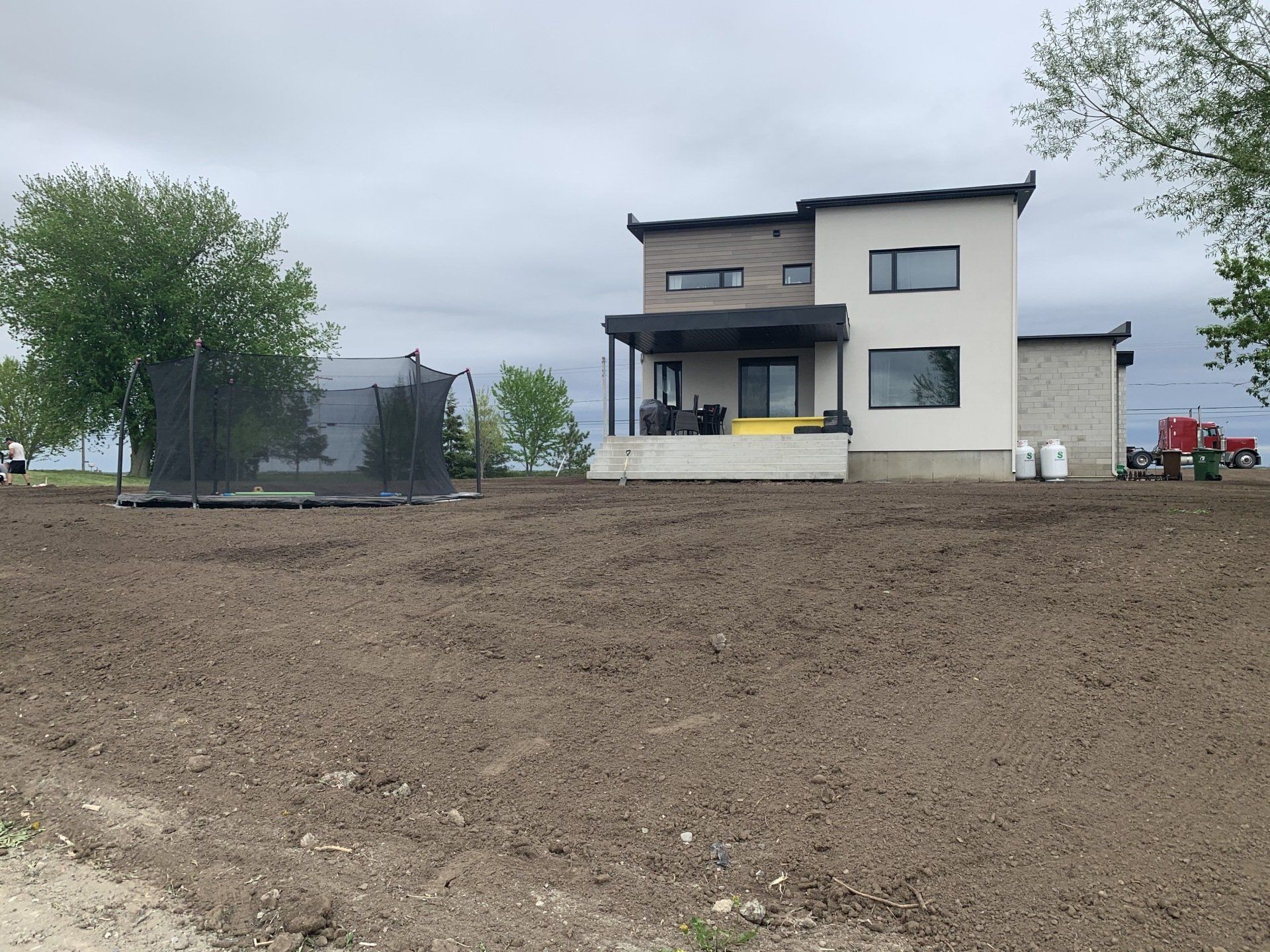 Une grande maison blanche se trouve au milieu d’un champ de terre