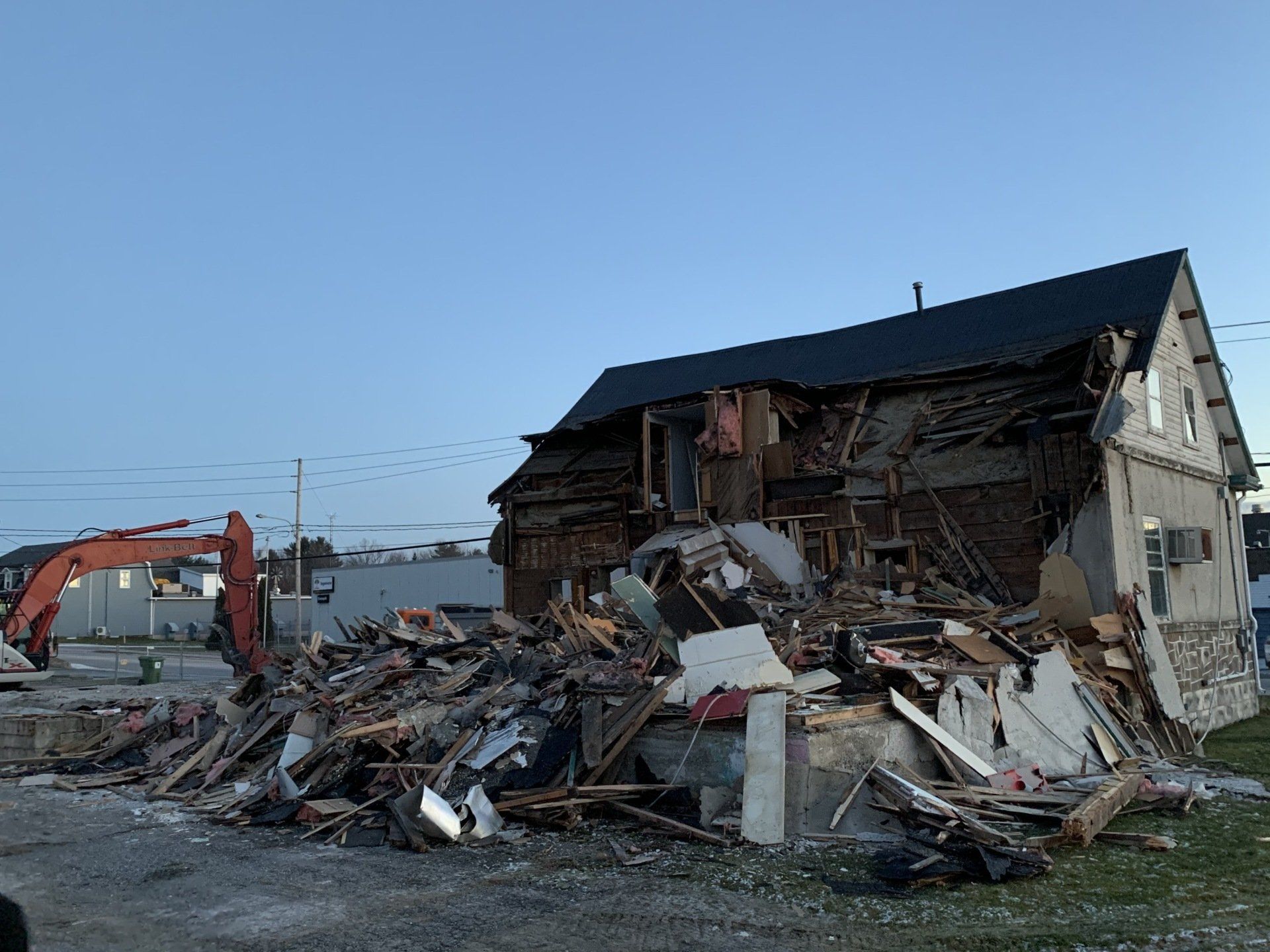 Une maison est démolie par une excavatrice.