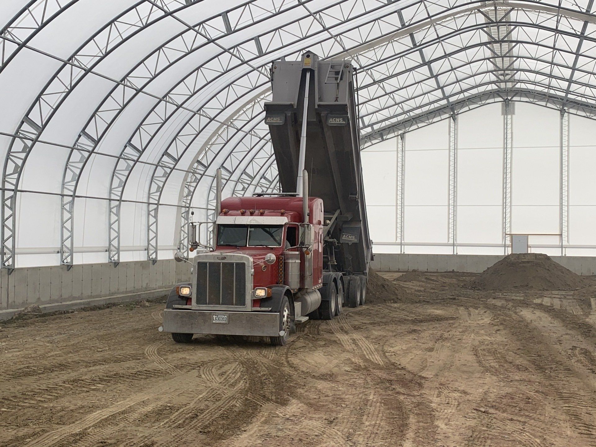 Un semi-remorque rouge traverse un champ de terre