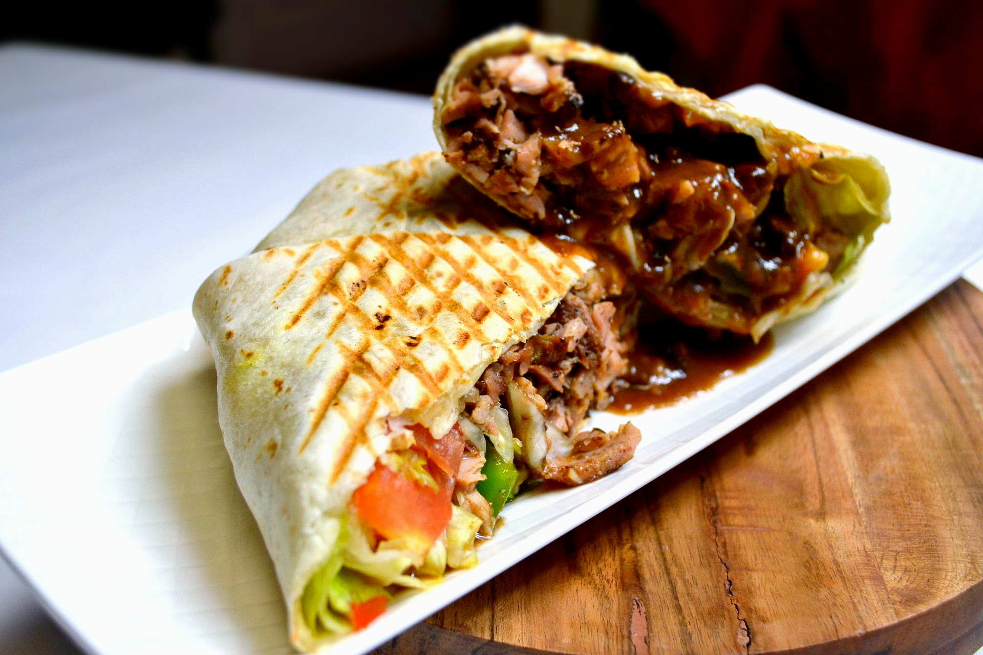 A burrito with meat and vegetables on a white plate