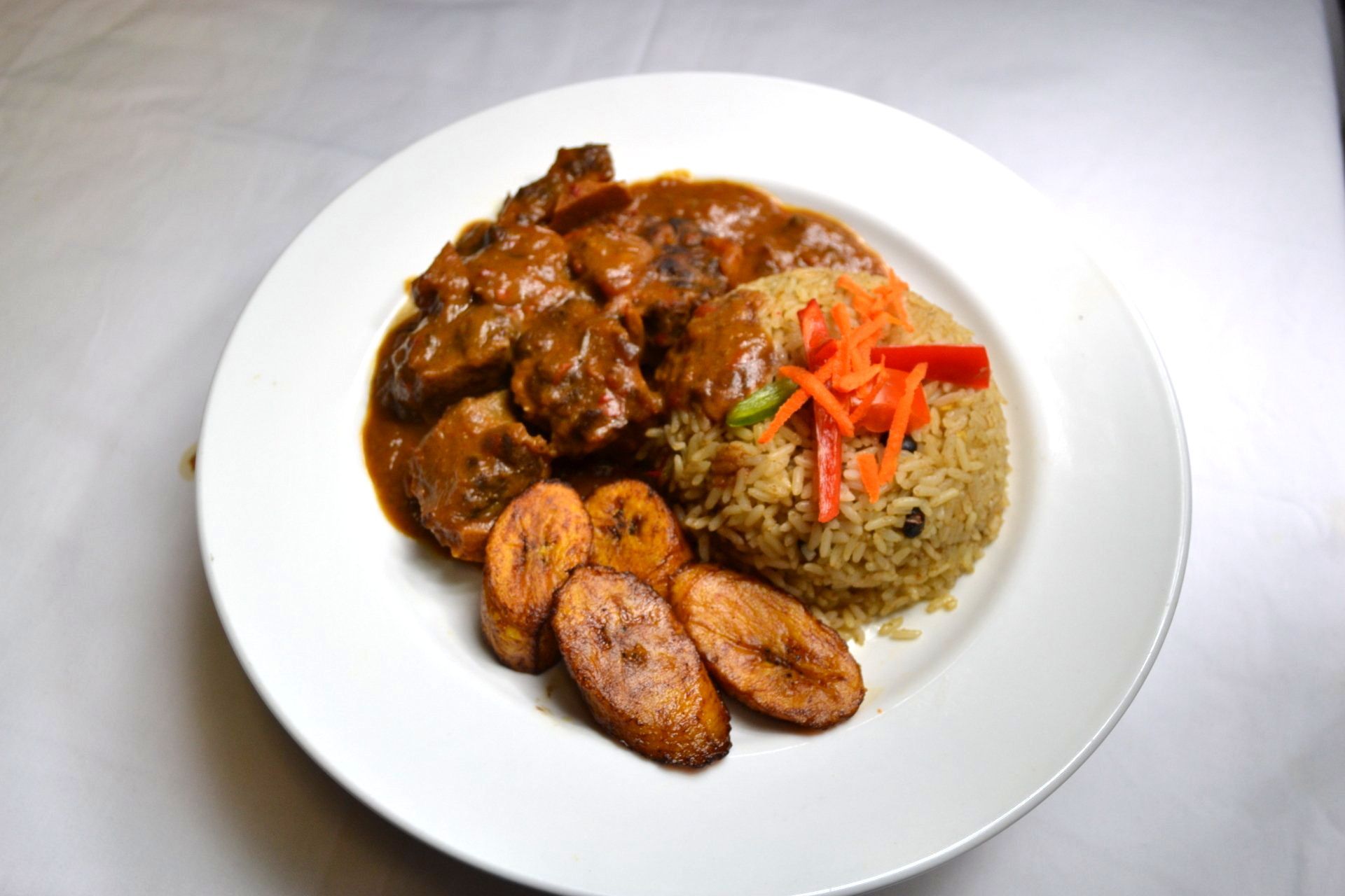 A plate of food with rice and plantains on a table.