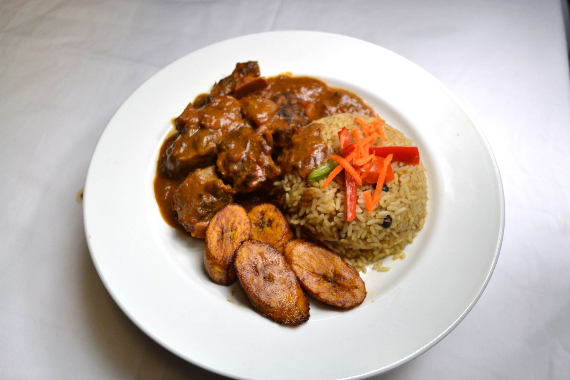 A plate of food with rice and plantains on a table.