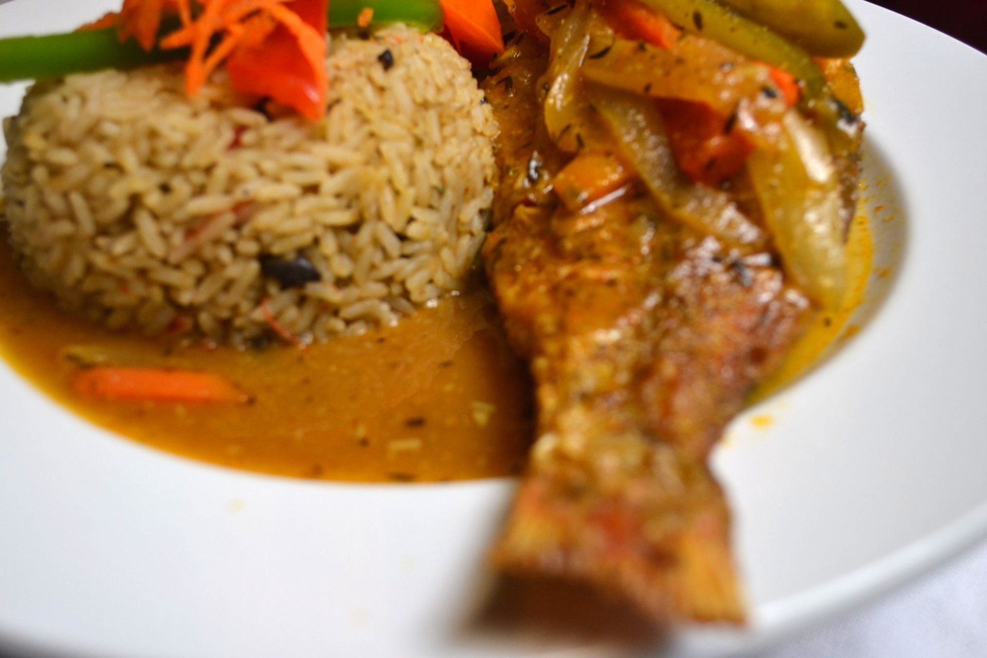A close up of a plate of food with rice and fish on a table.