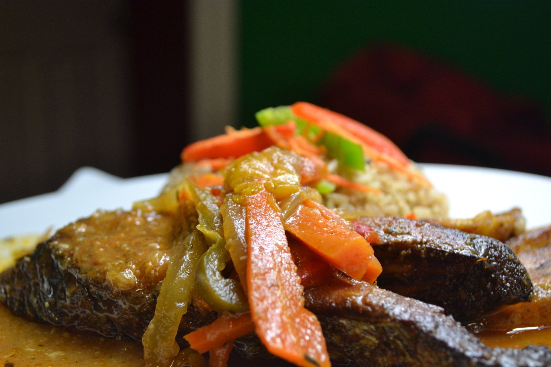 A close up of a plate of food with meat and vegetables on a table.