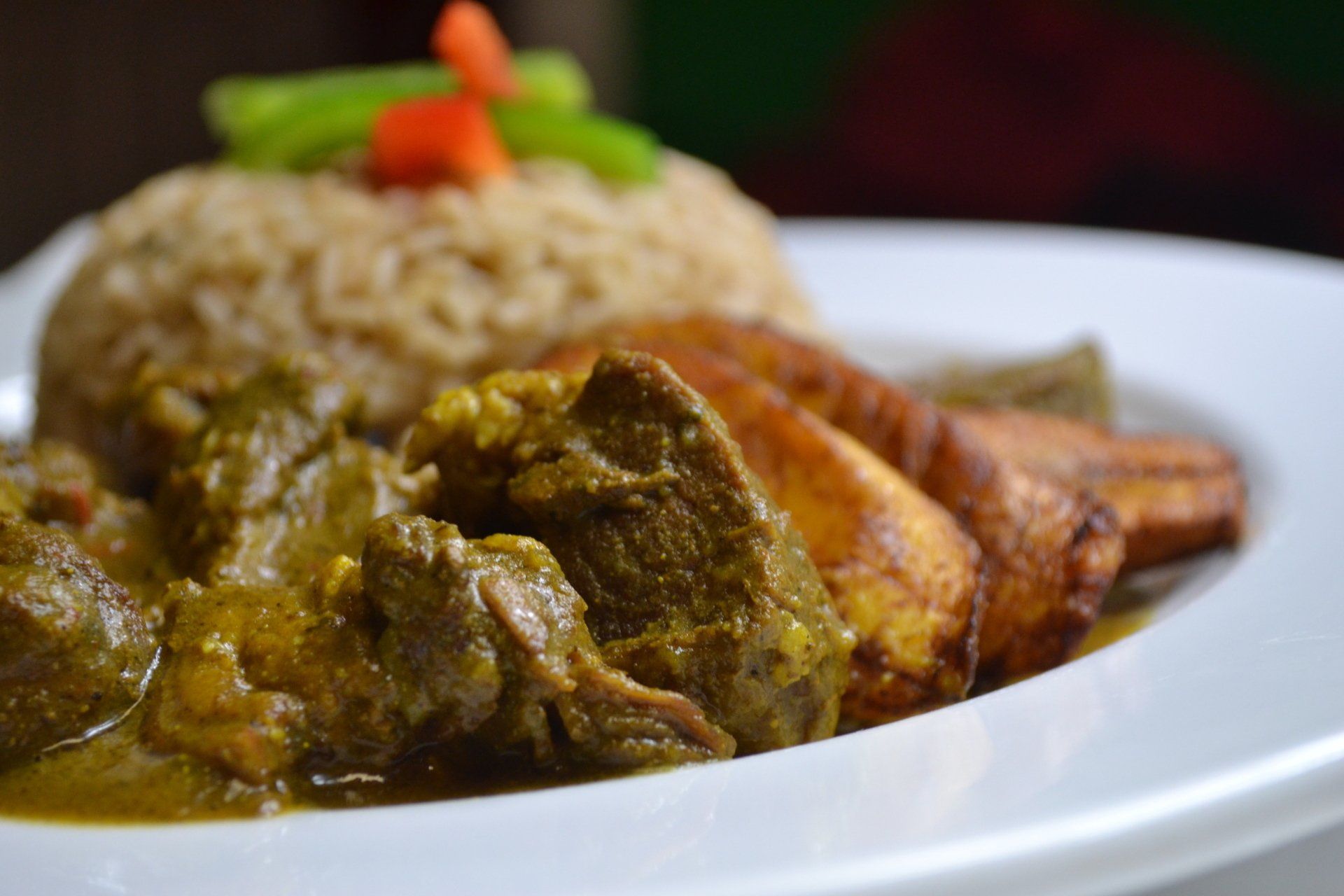 A white plate topped with rice , meat and vegetables.