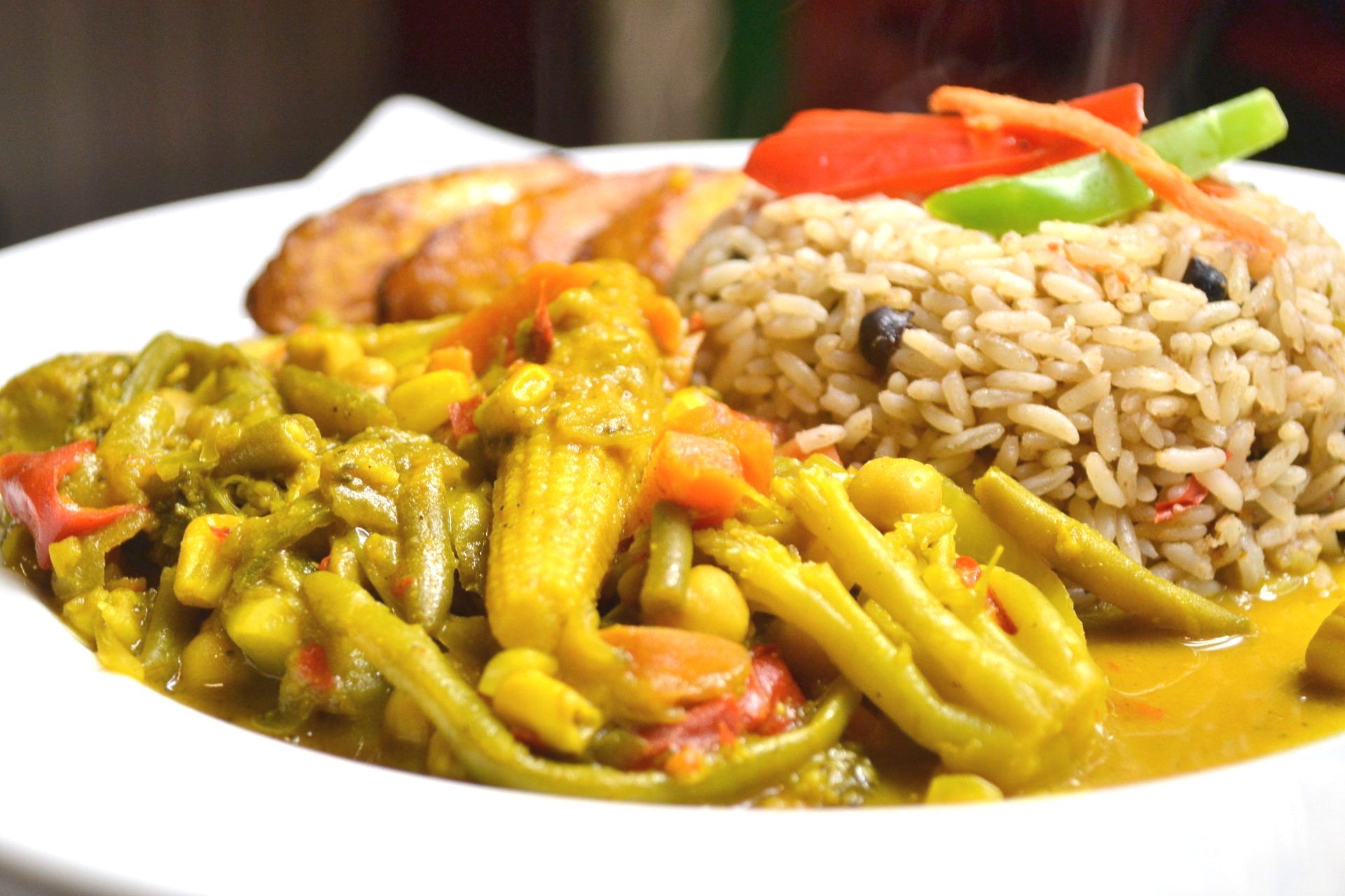 A close up of a plate of food with rice and vegetables on a table.