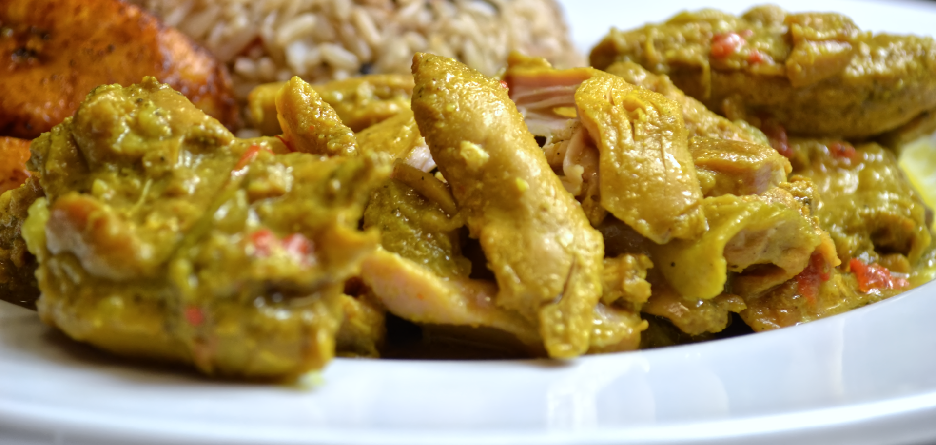 A white plate topped with chicken curry and rice.