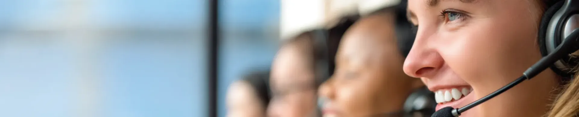 Pessoas usando fones de ouvido e sorrindo, em uma central de atendimento.