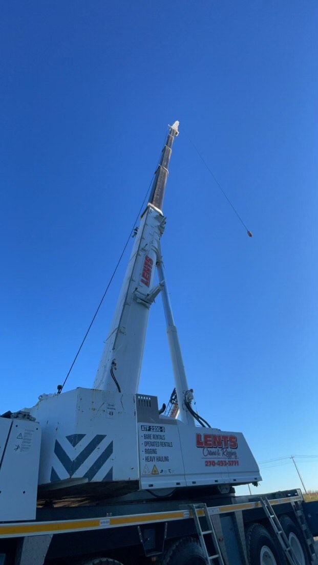 White crane against a clear blue sky. It's set up on a trailer, likely for lifting.