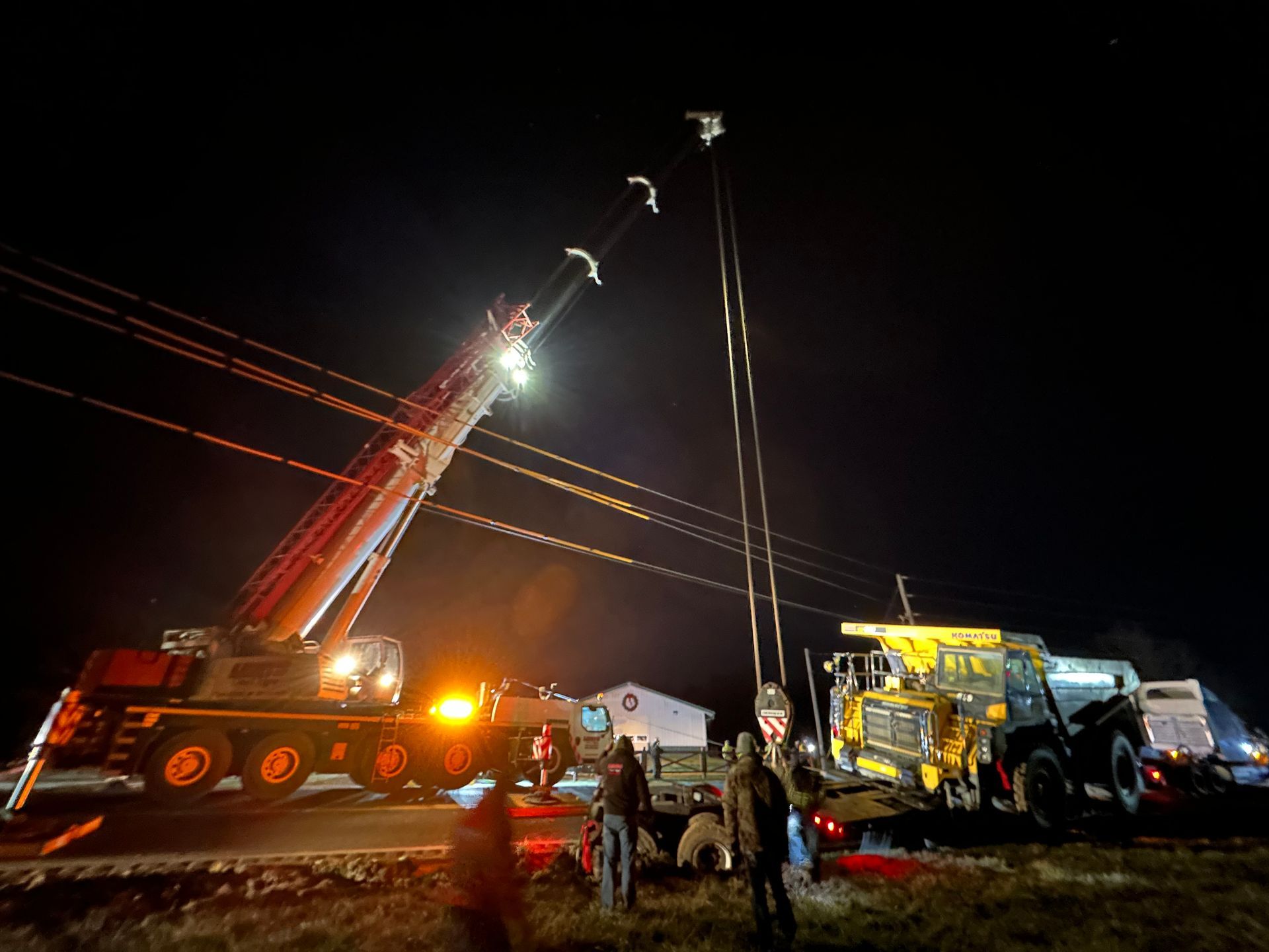 A large yellow truck is being towed by a crane at night