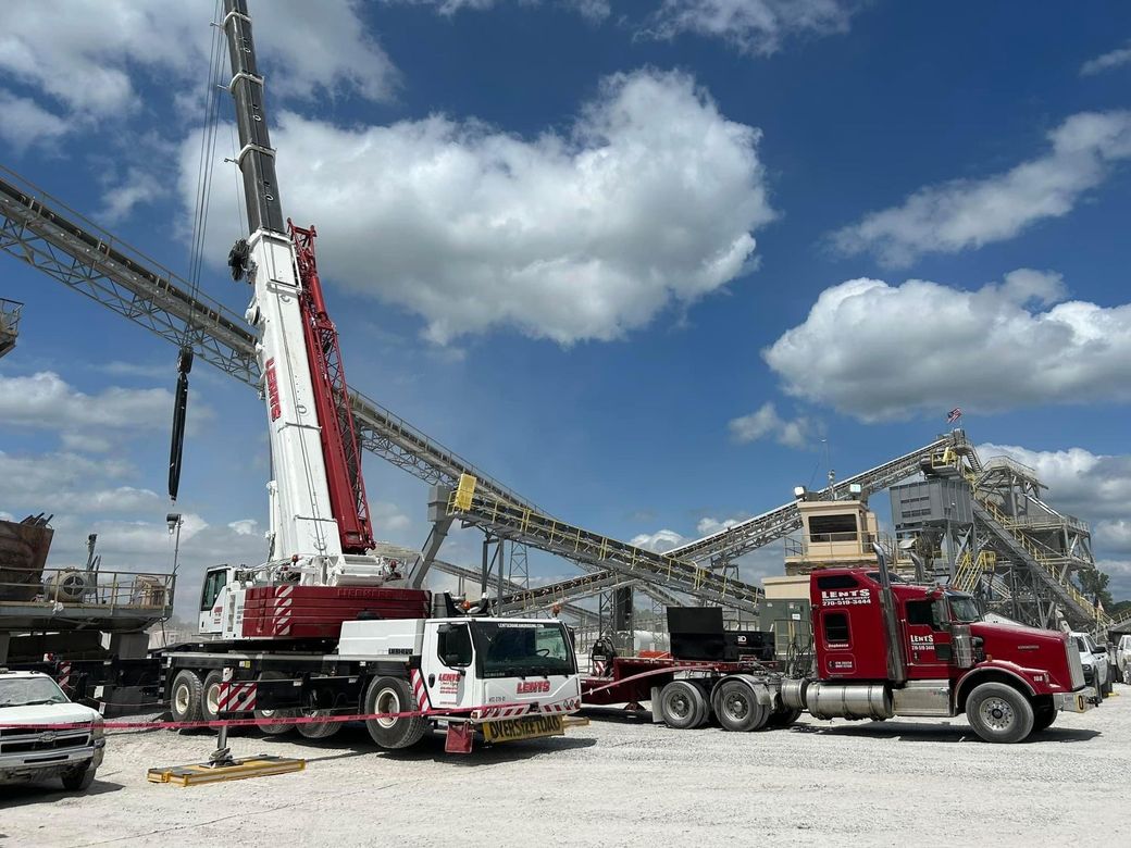 A large crane is sitting on top of a truck in a gravel lot.