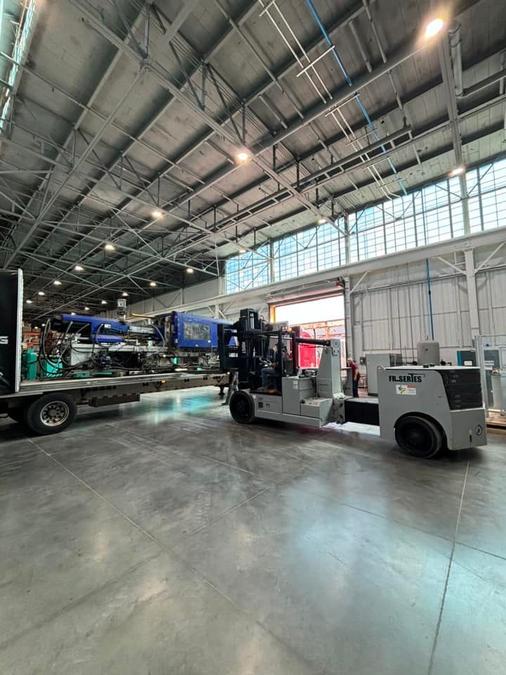 A forklift is moving a large machine in a warehouse.