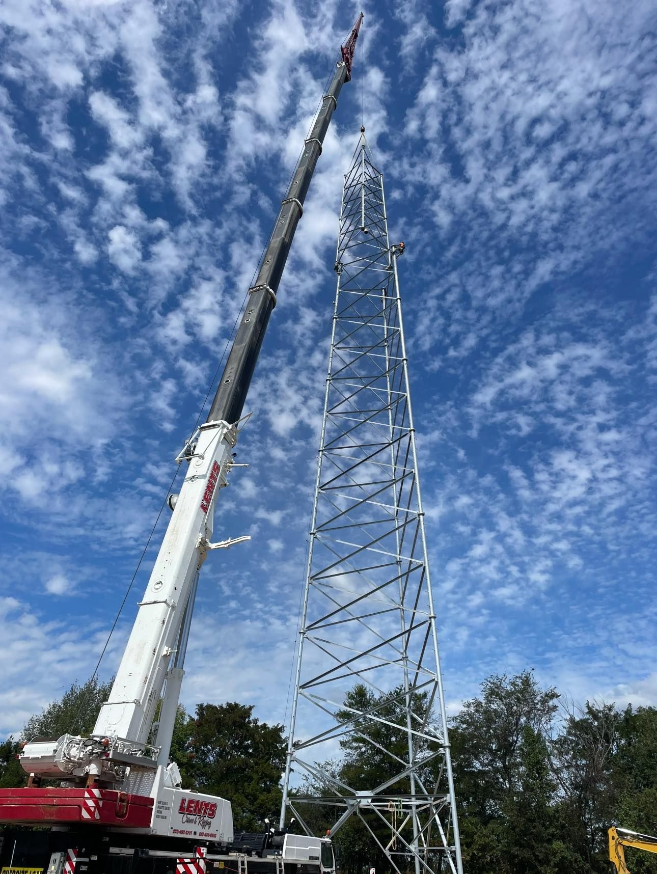 A large crane is lifting a very tall tower.