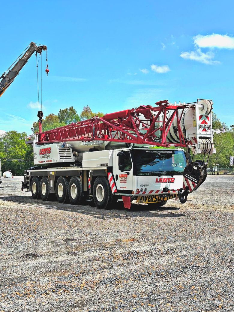 A large red and white crane is parked in a gravel lot.