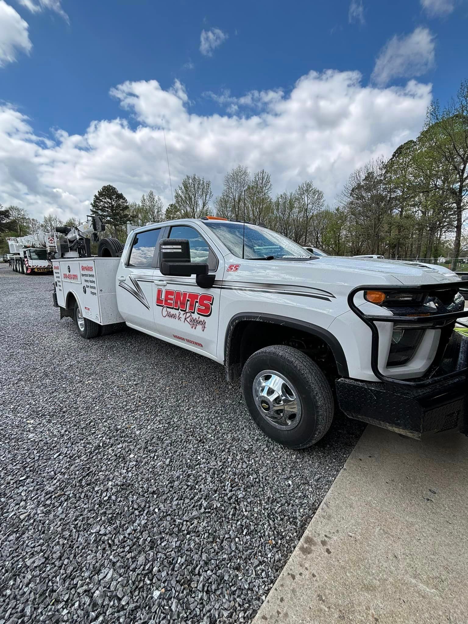 A white tow truck is parked in a gravel lot.