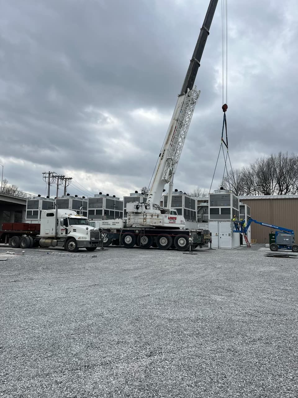 A large crane is lifting a building in a gravel lot.
