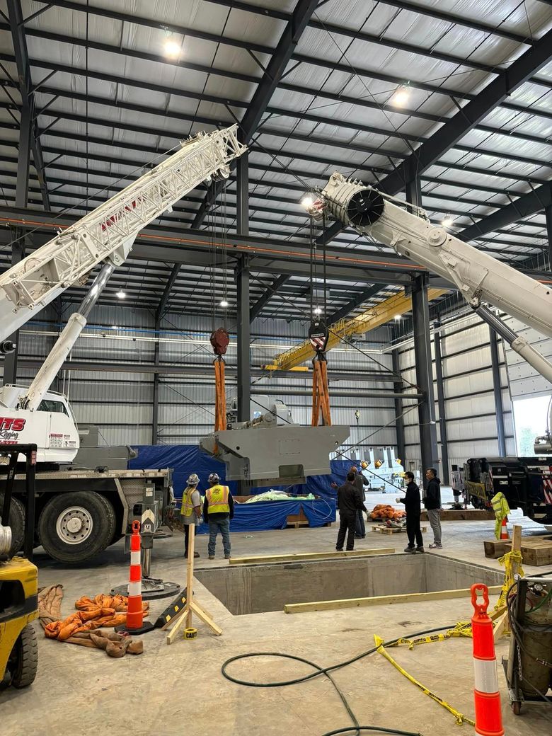 A crane is lifting a large piece of metal in a warehouse.