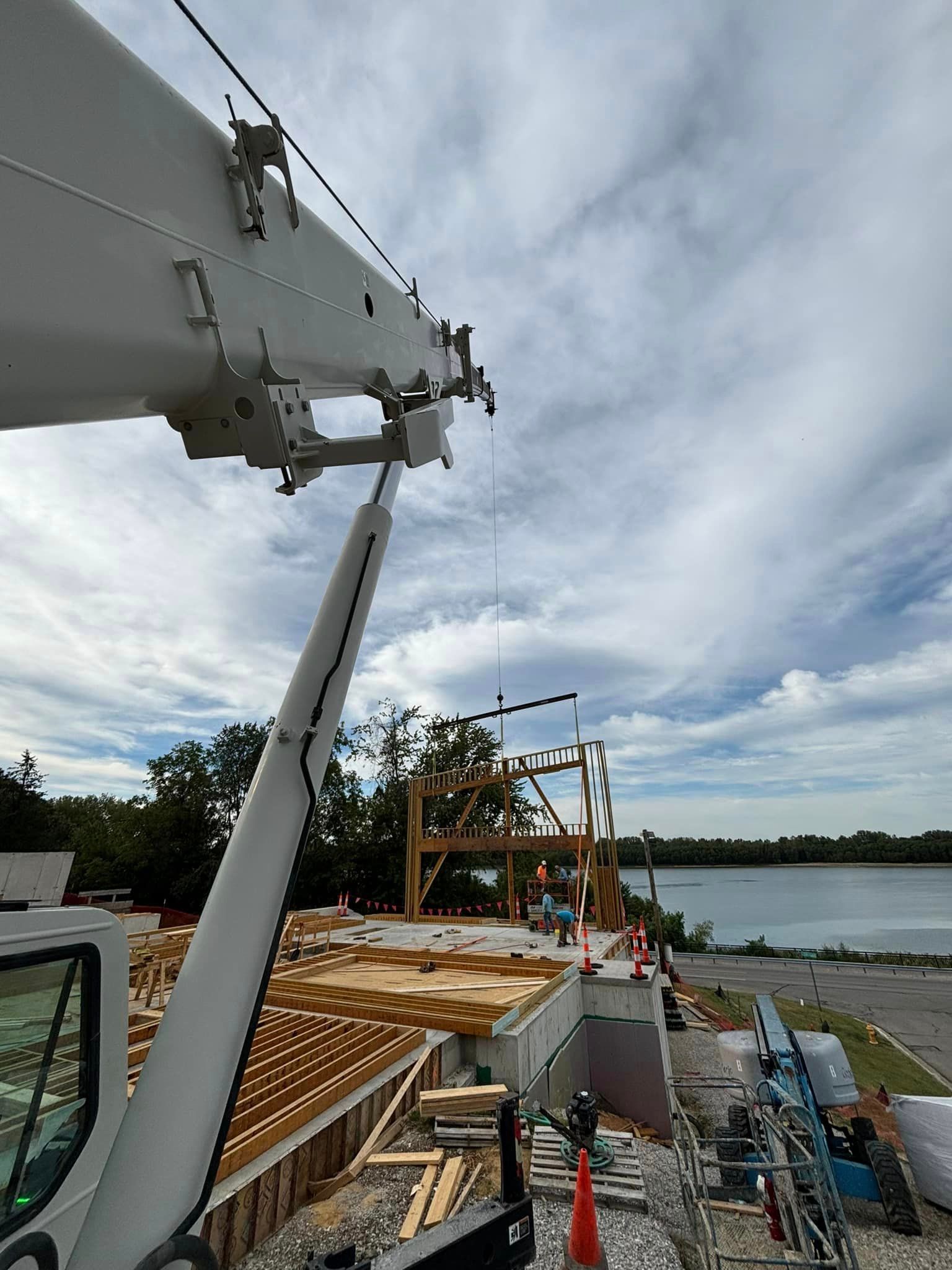 A large white crane is sitting on top of a construction site next to a body of water.