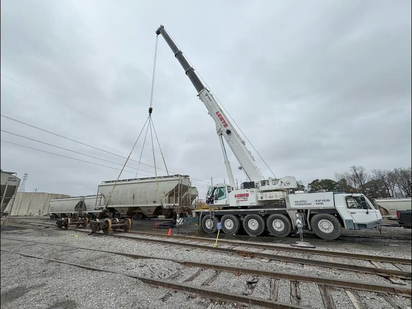 A large crane is lifting a train car in a train yard.