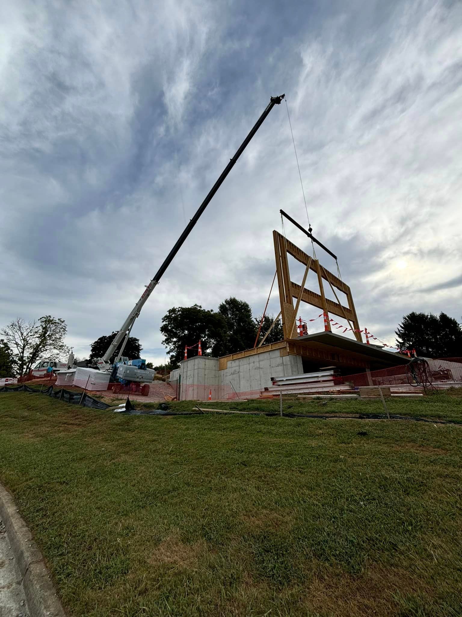 A crane is lifting a piece of wood on top of a building.