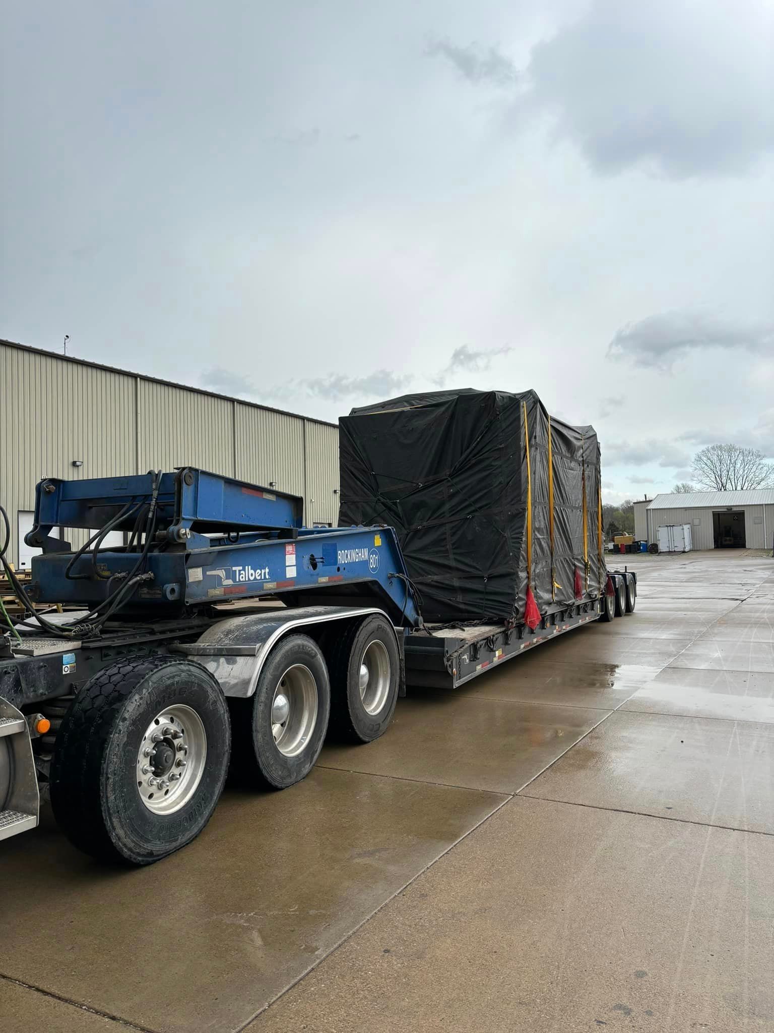 A semi truck is parked in a parking lot next to a building.