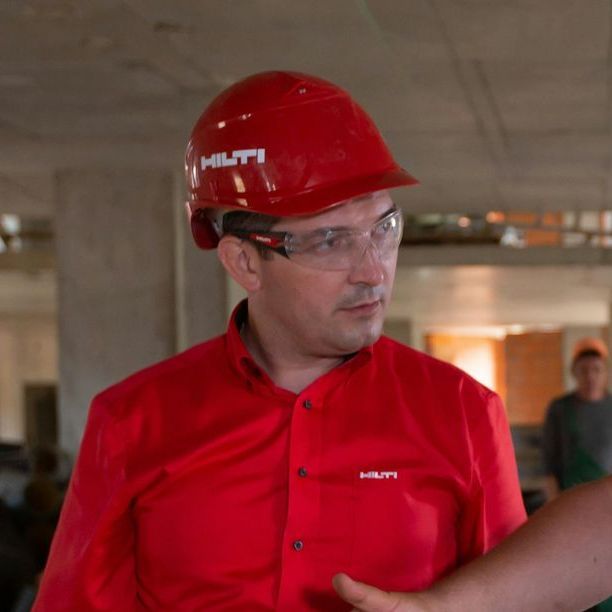 A man wearing a red shirt and a red helmet with the word hilti on it