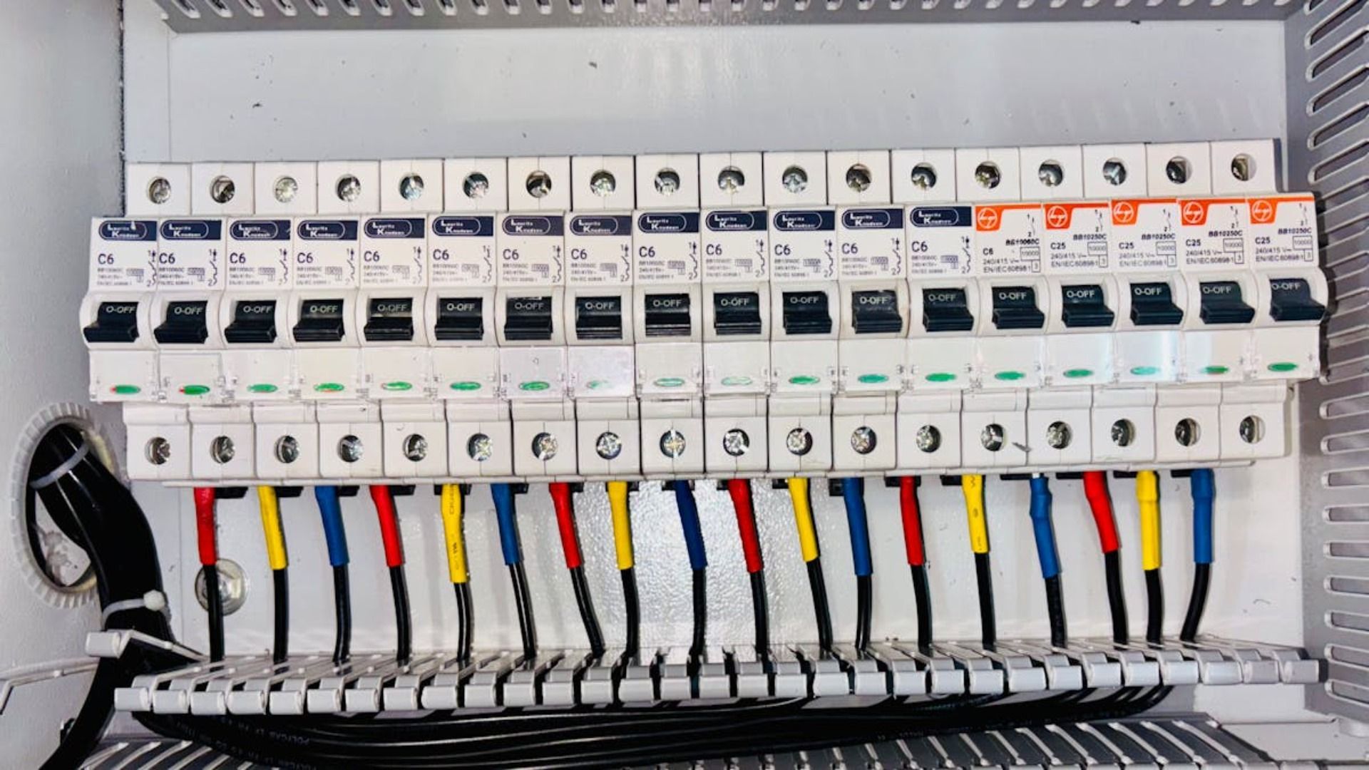 Panel eléctrico con filas de disyuntores y cables.
