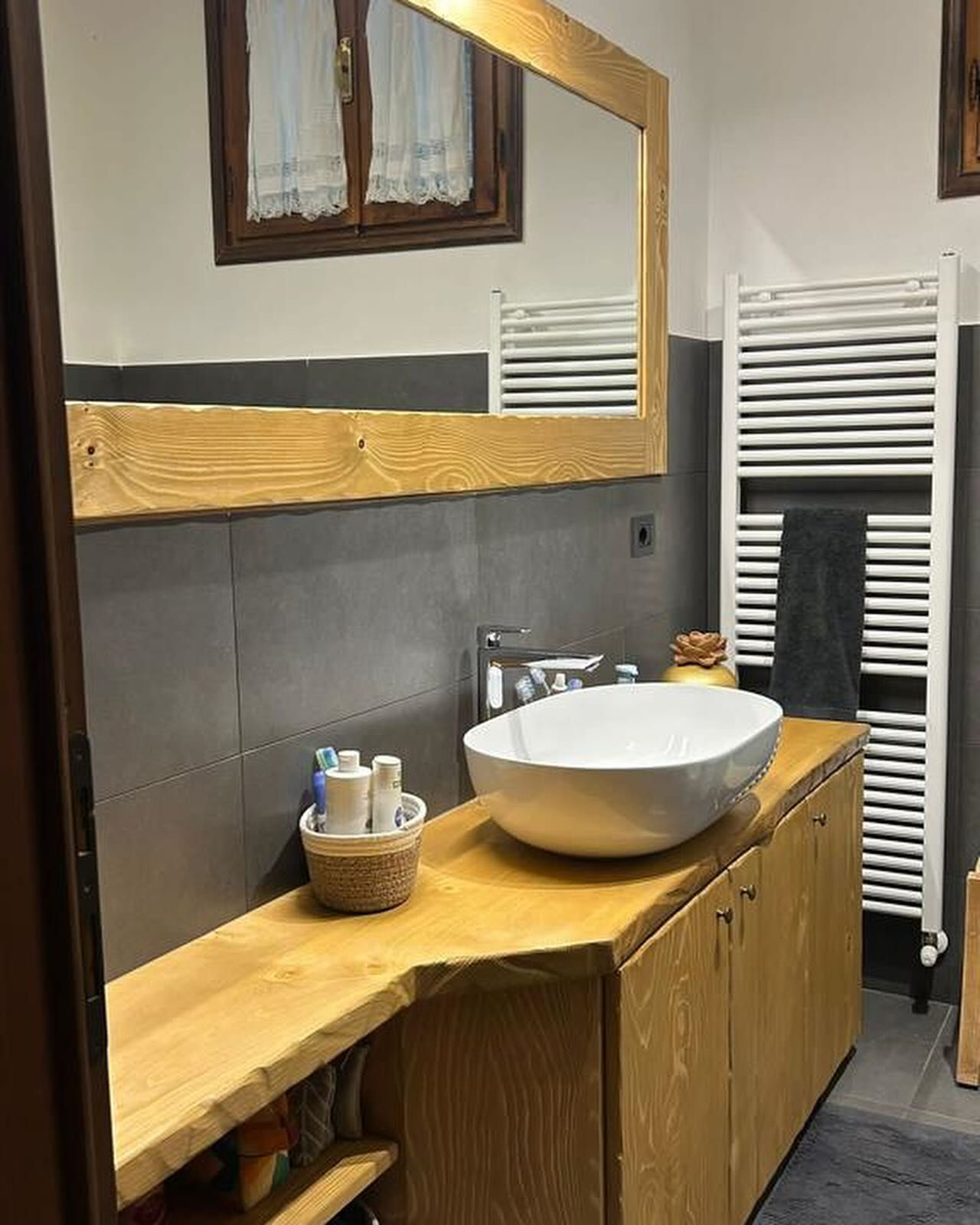 Bagno con mobile lavabo in legno, lavabo ovale, grande specchio e scaldasalviette. 