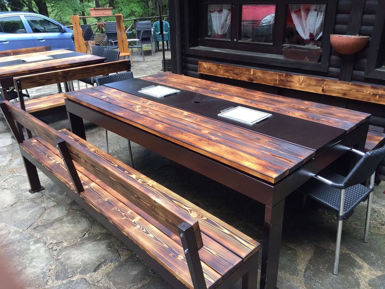 Set da pranzo per esterni con tavoli e panche in legno, strutture marrone scuro.