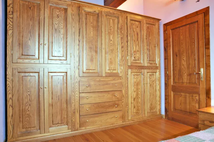 Armadio in legno con cassetti e un'anta a destra, legno marrone chiaro.